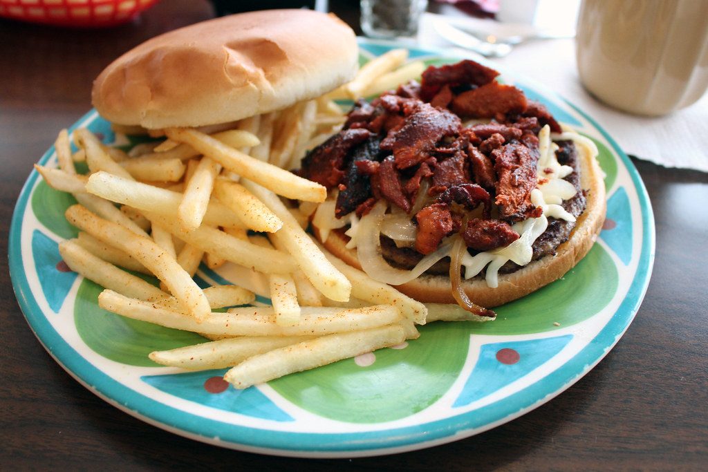 Hamburguesa con cebolla crispy y papas en plato de colores