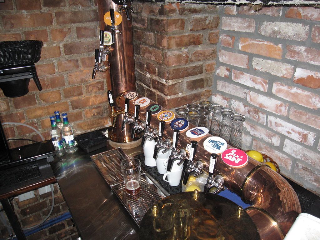Barra con canillas de cerveza frente a una pared de ladrillo