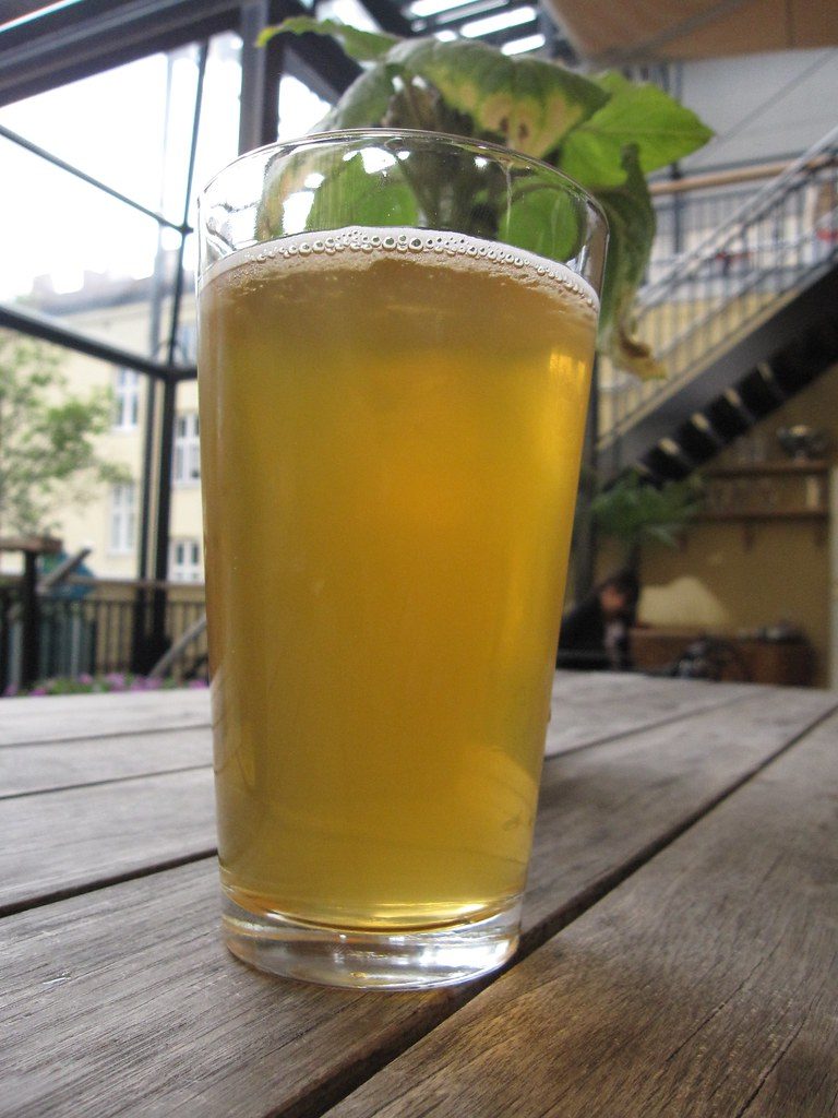 Pinta de cerveza rubia sobre una mesa de madera