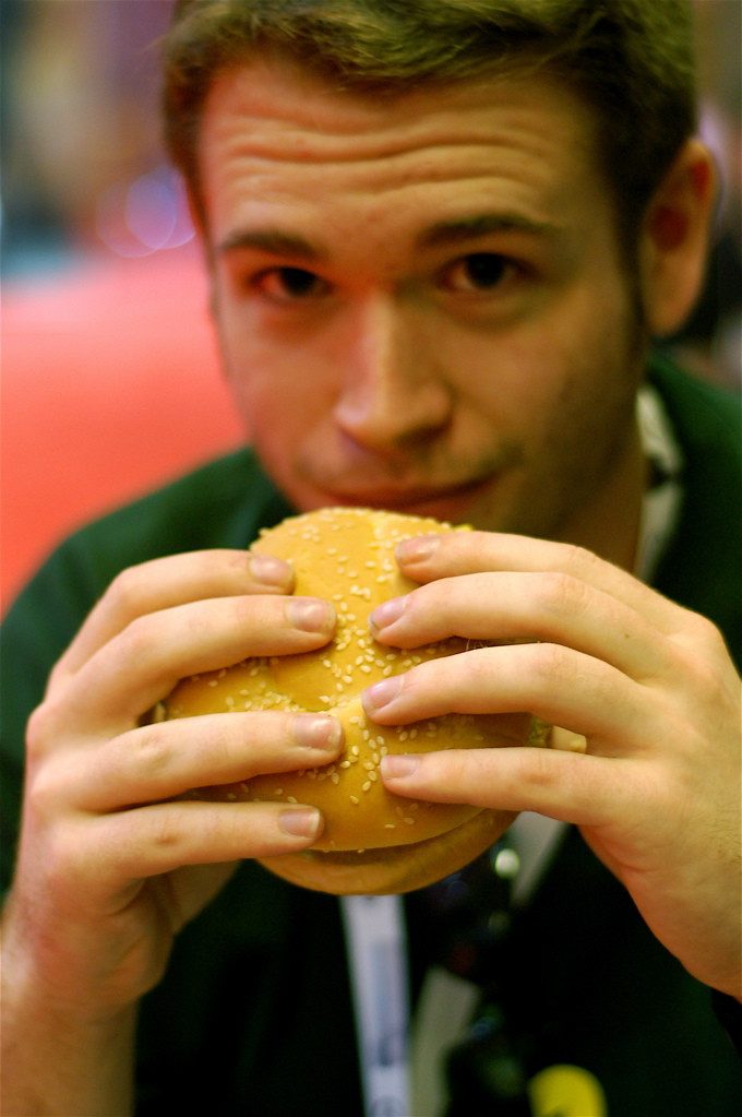 Persona mordiendo una hamburguesa con las dos manos