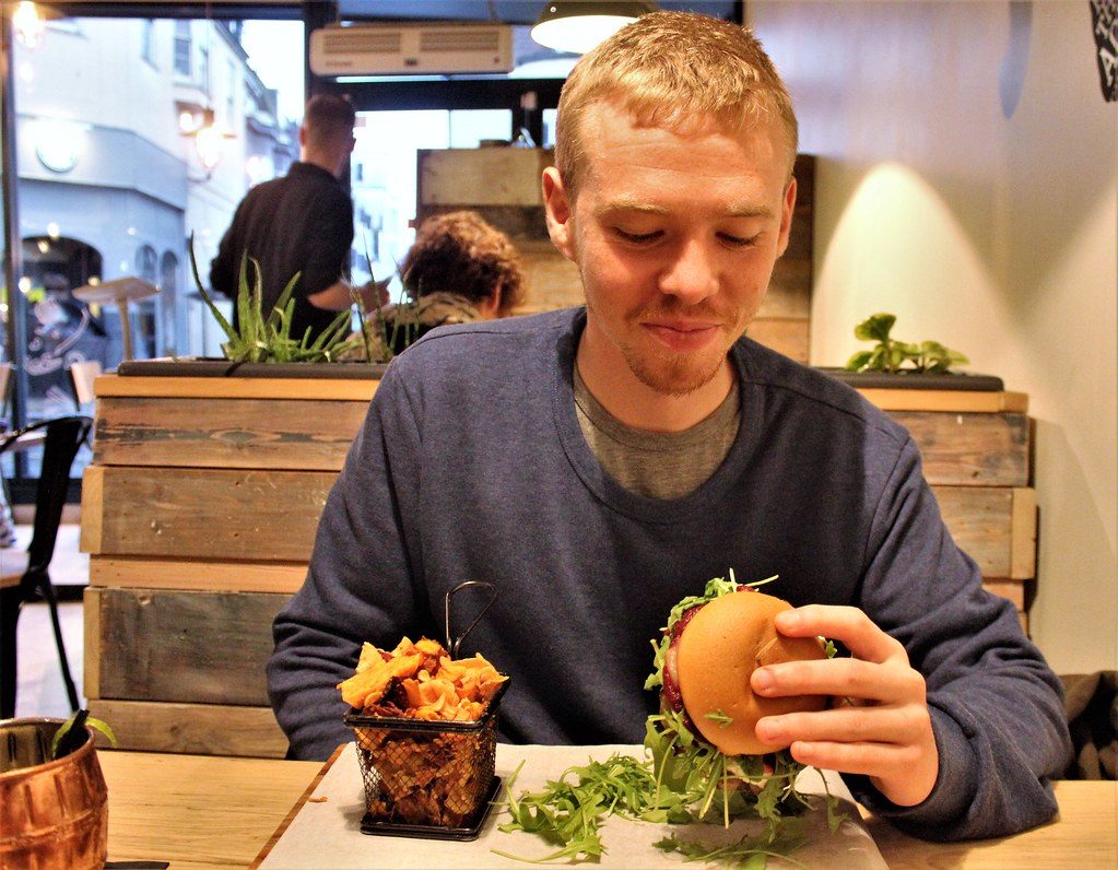 Cliente sonriendo frente a una hamburguesa con papas