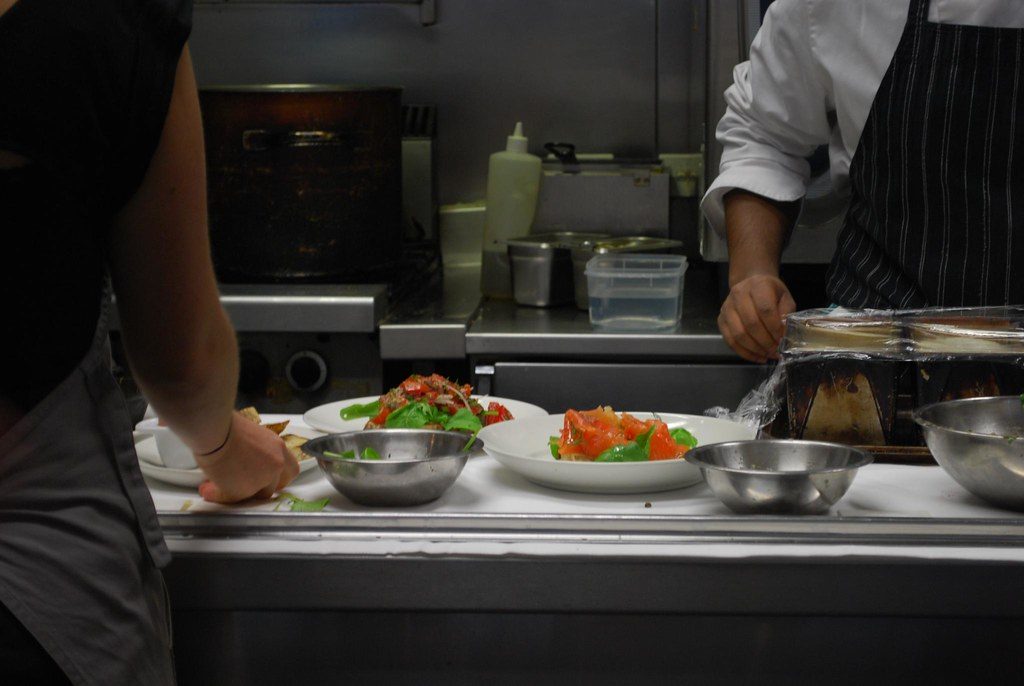 Cocineros armando platos en una cocina de acero