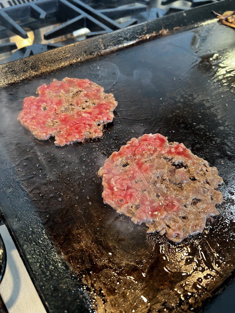 Dos bollos de carne aplastados sobre la plancha