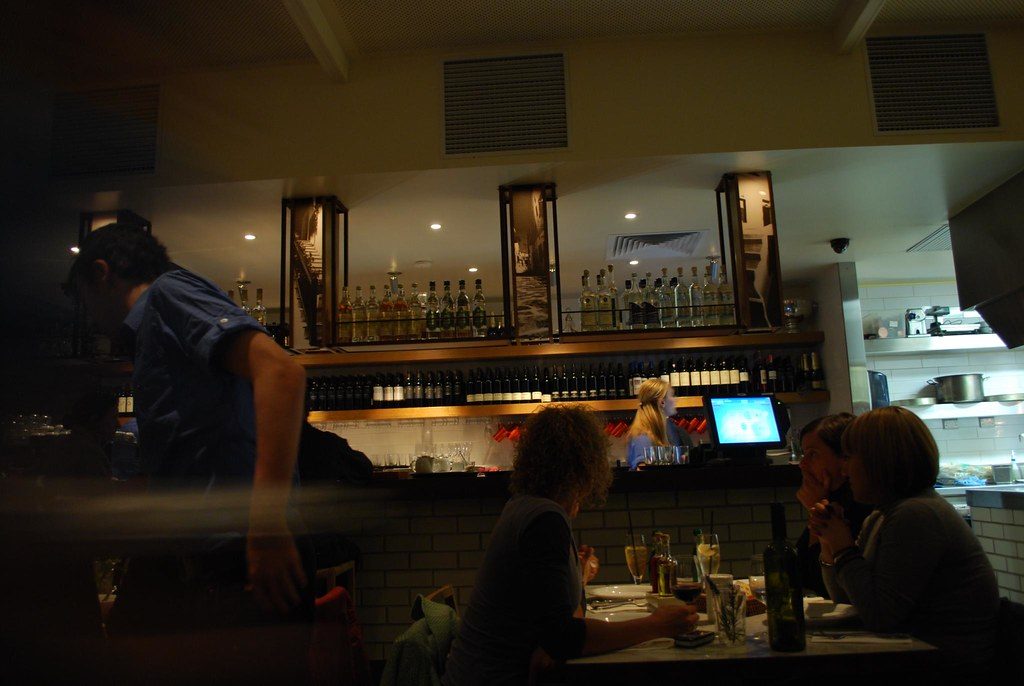 Salón del local de noche, con la barra iluminada al fondo