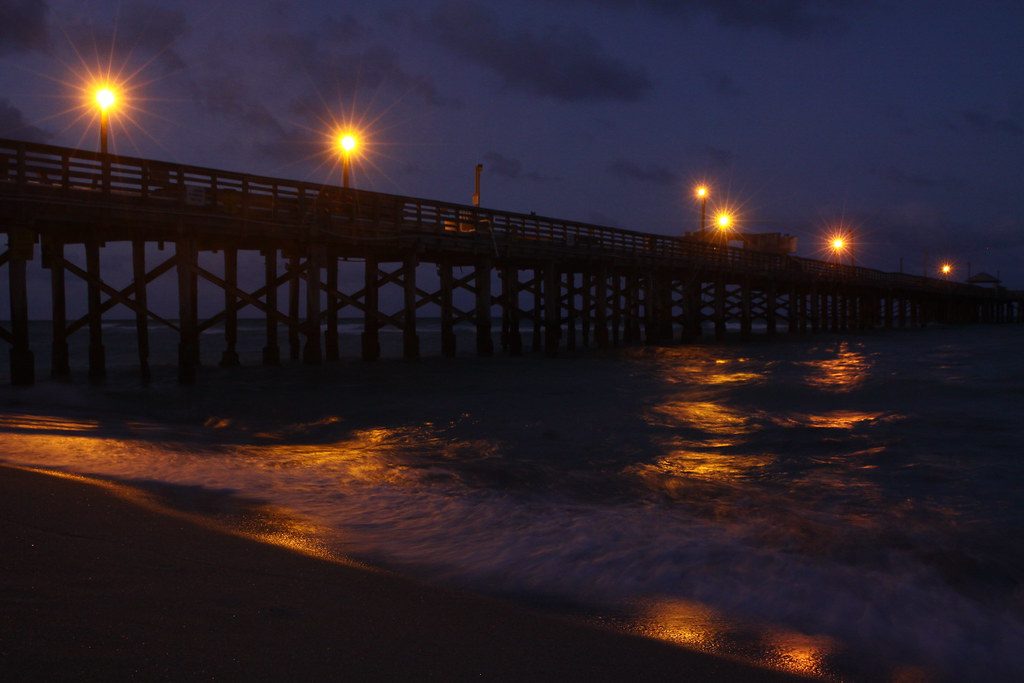 Muelle de noche con faroles encendidos reflejados en el agua
