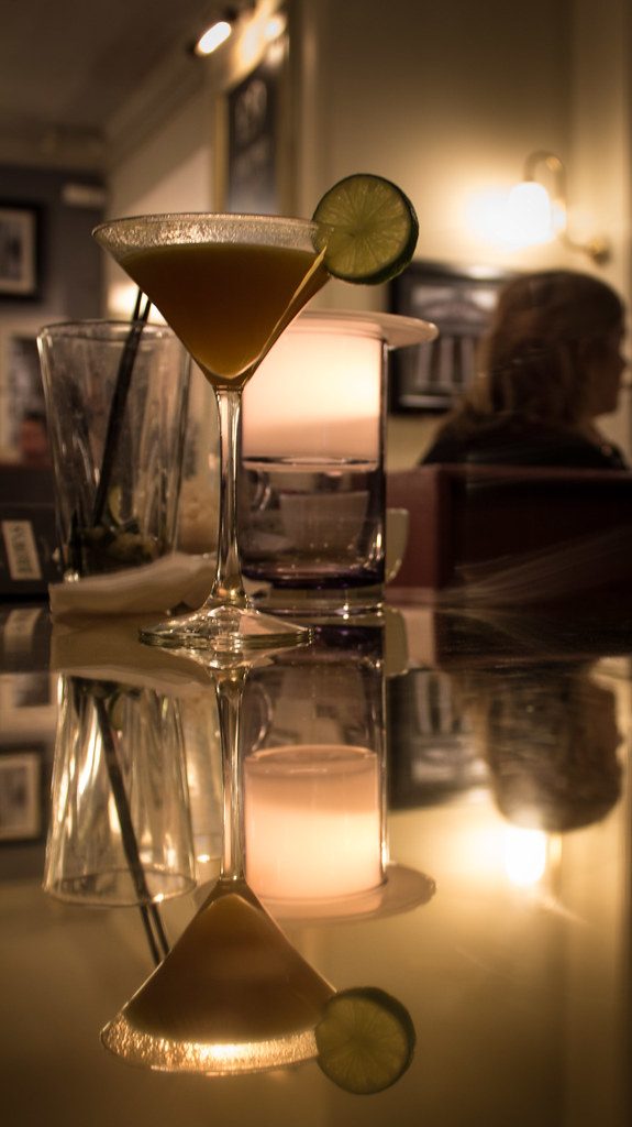 Trago en copa sobre la barra con velas
